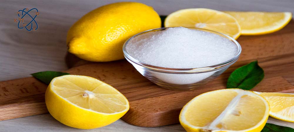 کریستالهای سفید اسید سیتریک داخل کاسه و تکه های لیمو ترش