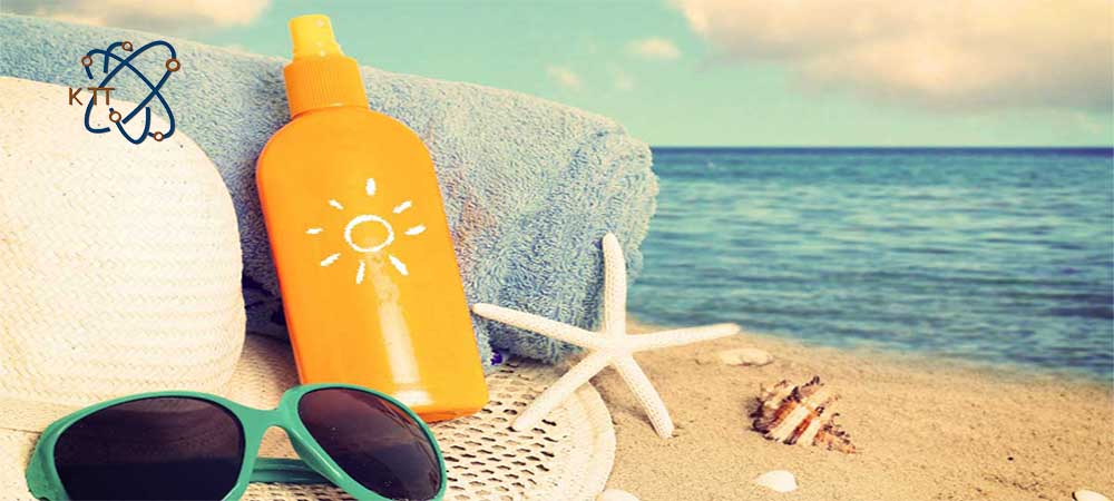 قوطی ضد آفتاب نارنجی، عینک آفتابی، حوله آبی برروی شنهای ساحل دریا