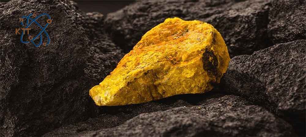 یک قطعه سنگ زرد رنگ اورانیوم بر روی سنگهای خاکستری تیره در معدن