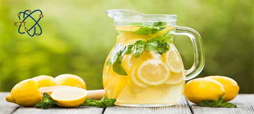 یک پارچ شیشه ای حاوی برشهای نعناع و لیموترش زرد در کنار تعدادی لیمو ترش زرد 
